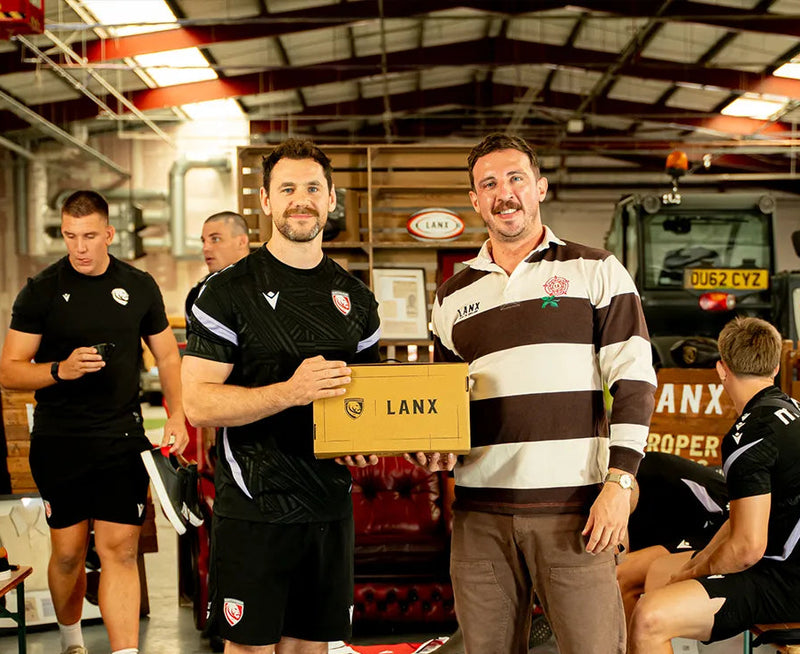 Two men holding a box with 'LANX' branding in an indoor setting.