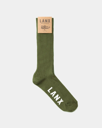 An olive green ribbed crew sock with 'LANX' printed in white on the toe and a tan paper brand tag at the cuff, shown against a light gray background.