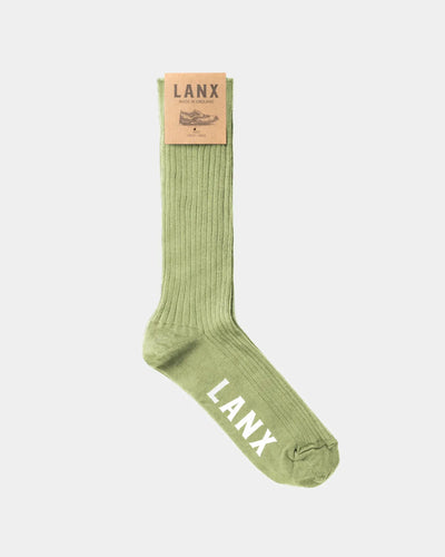A single light olive green ribbed sock with 'LANX' printed in white on the toe, featuring a tan paper brand tag at the cuff, shown against a light gray background.